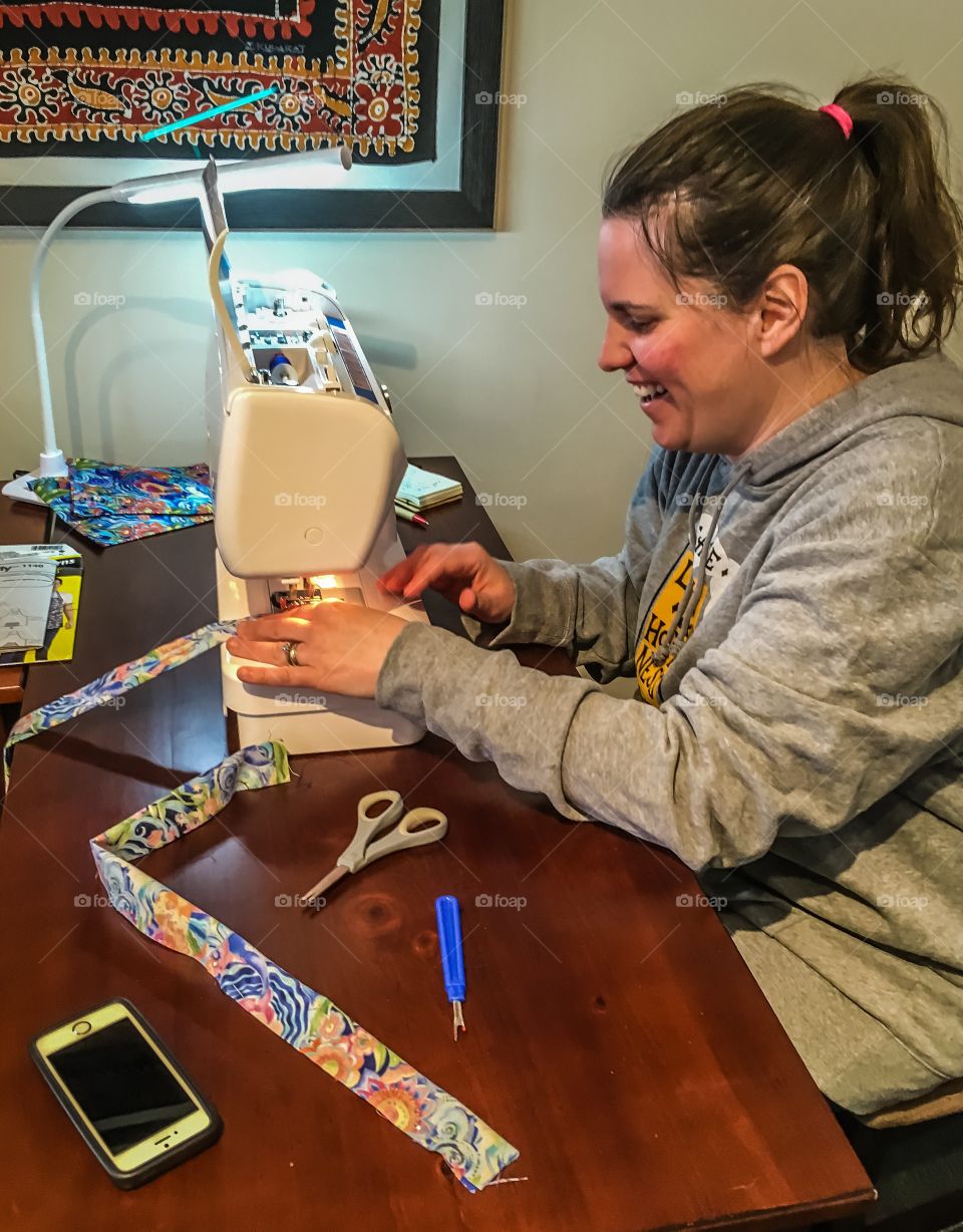 Woman sewing on a sewing machine.  She is taking sewing lessons, so she is a beginner. 