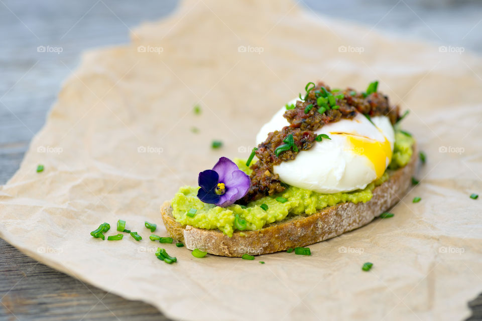 Delicious open sandwich made of avocado, tapenade, pouch-egg on chiabatta