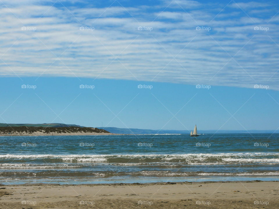 Sand, waves, white sails, distant hills