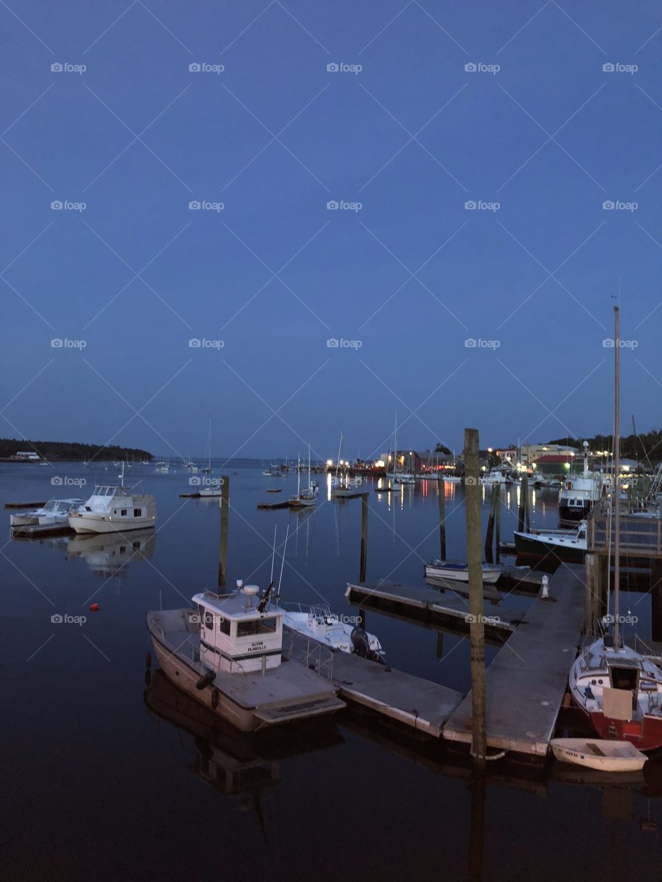 I photographed this scenic view of Belfast Harbor and the shipyard in Belfast, Maine USA, after watching the sun go down from the footbridge. Note the lights reflecting on the surface of the placid water.