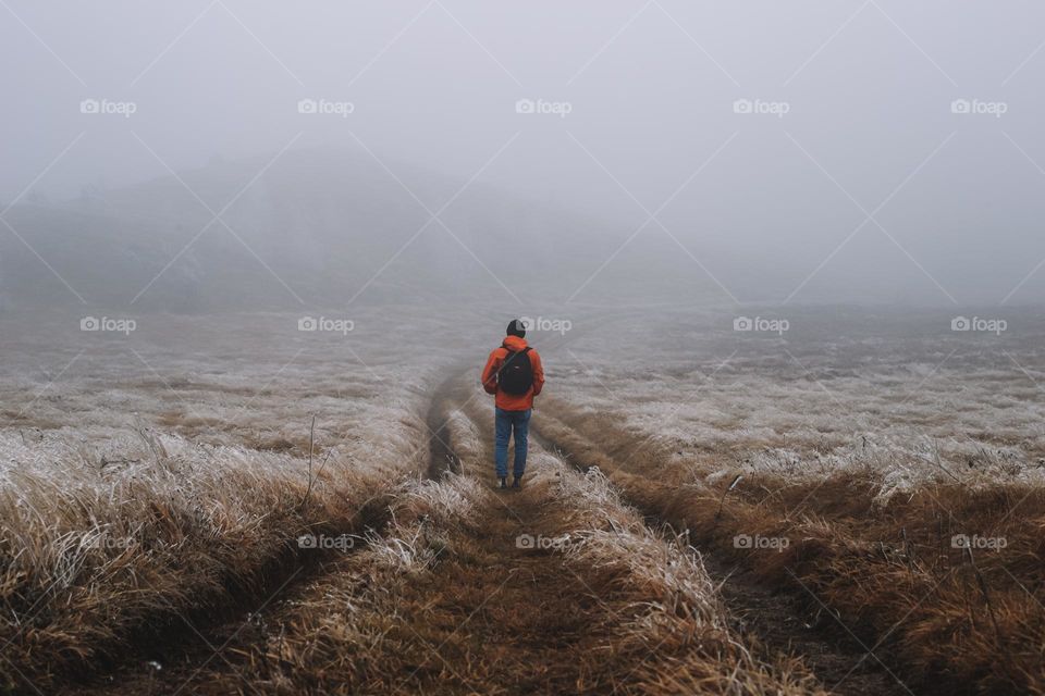 Male hiker walking on field during foggy weather 