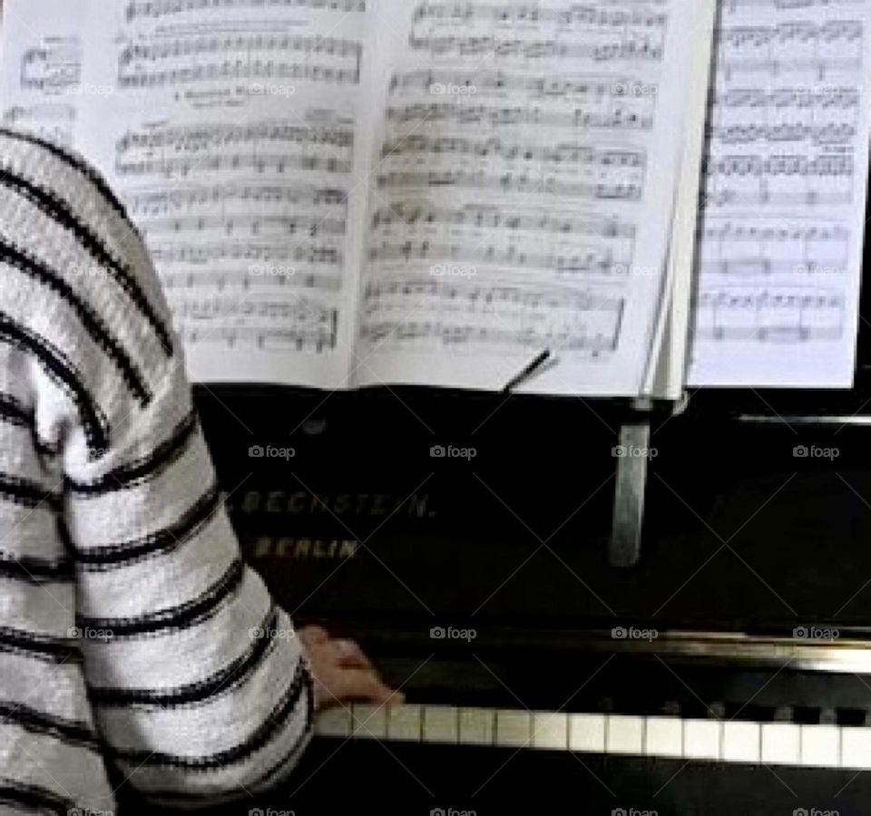 Person reading sheet music and playing the piano 