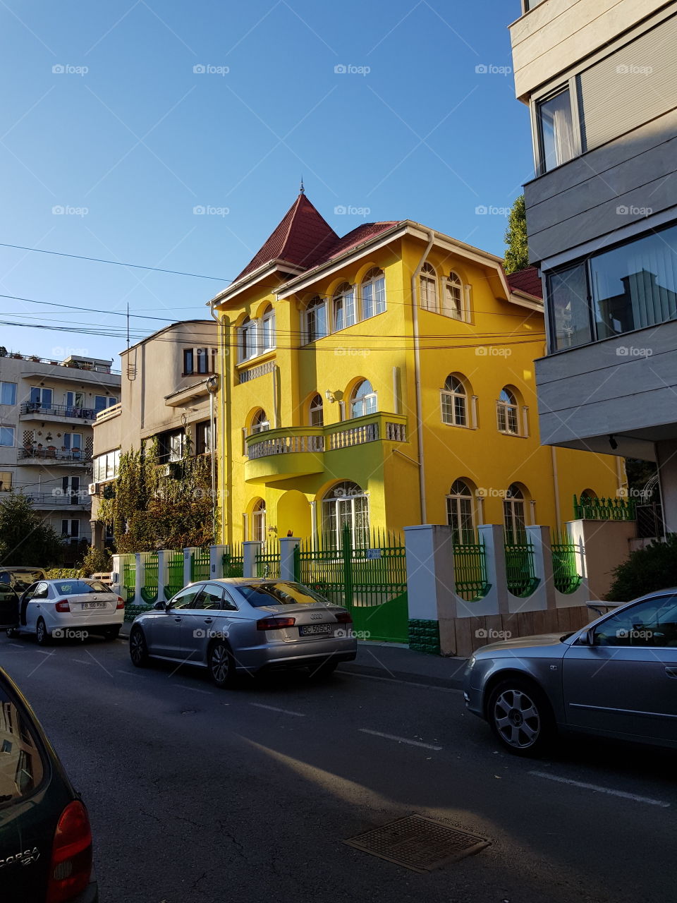 Bright yellow house between greyish buildings in a city