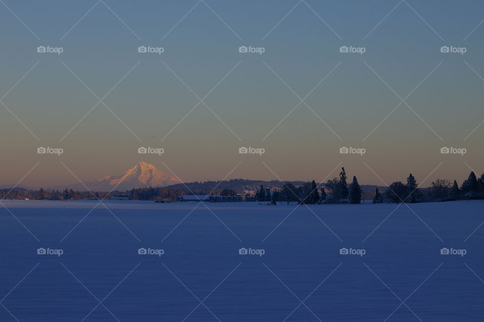 Alpenglow over snow covered field