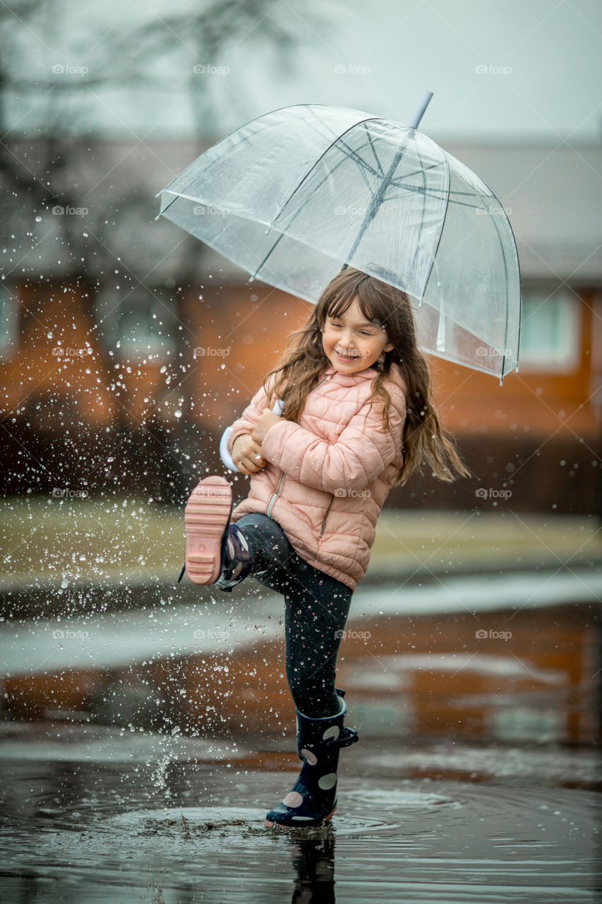 Little girl have fun under the rain.