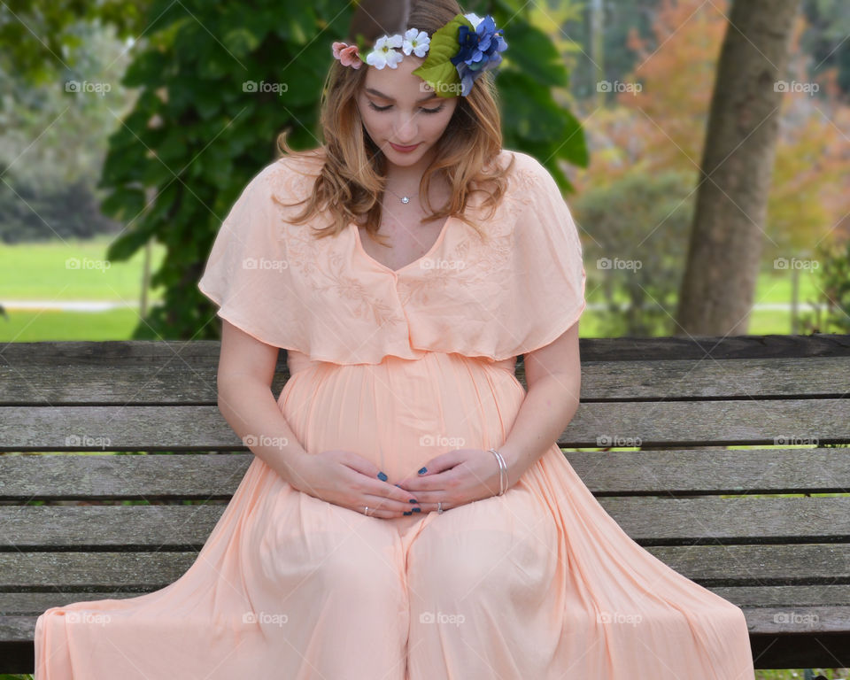 Beautiful pregnant woman sitting on bench