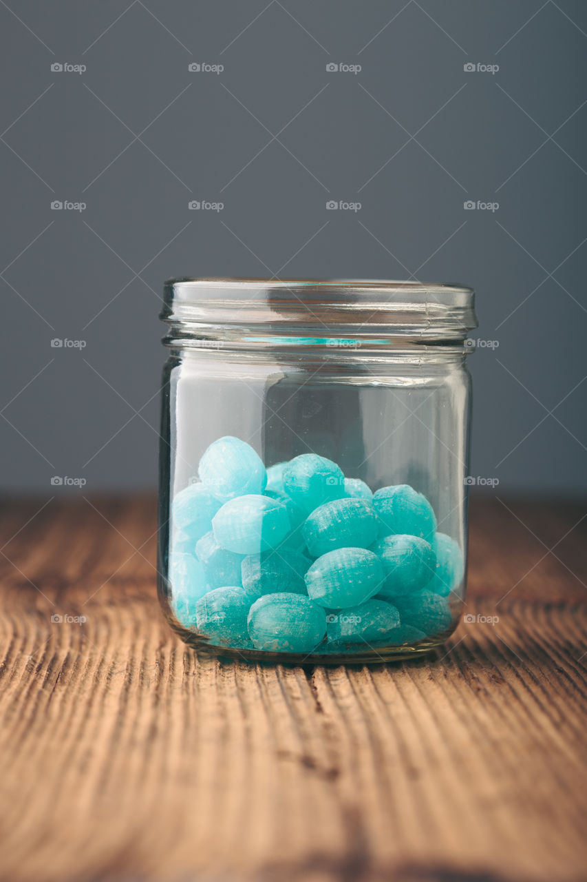 Jar filled with mint candies on wooden table