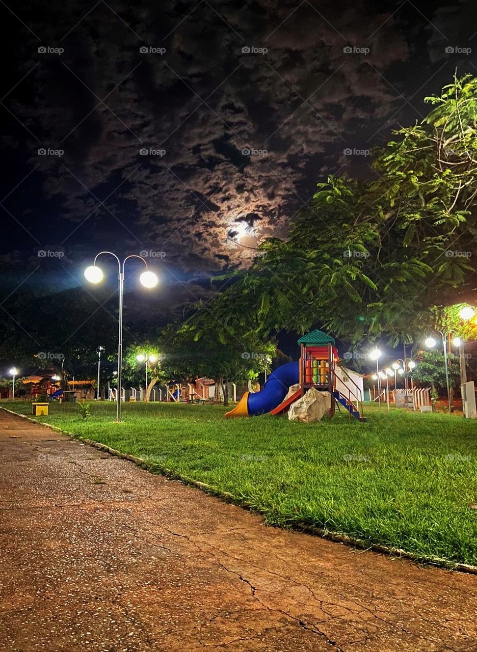 A colorful playground illuminated by moonlight on a cloudy night. How magical!