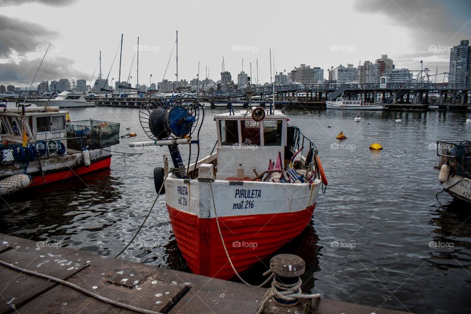 Nombre: La roja piruleta. Una barca clásica pesquera, en el muelle descansando. con colores fuertes y un cielo contrastado.