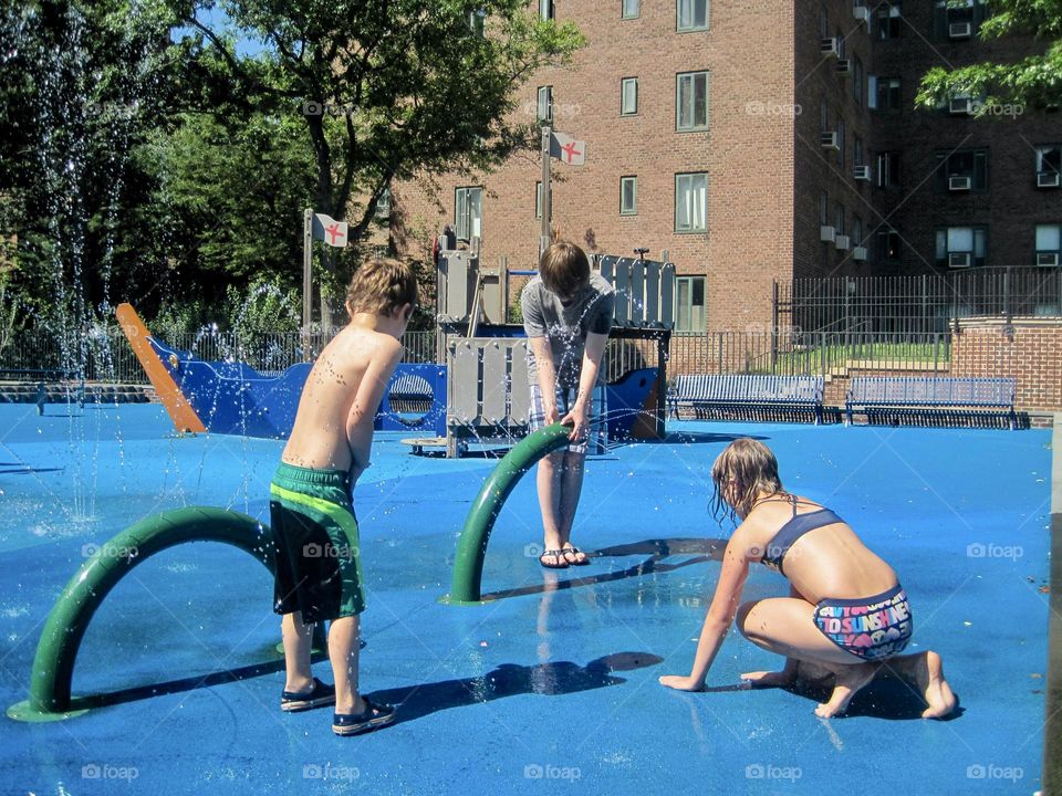 Kids playing on a splash in the summer, in the city.