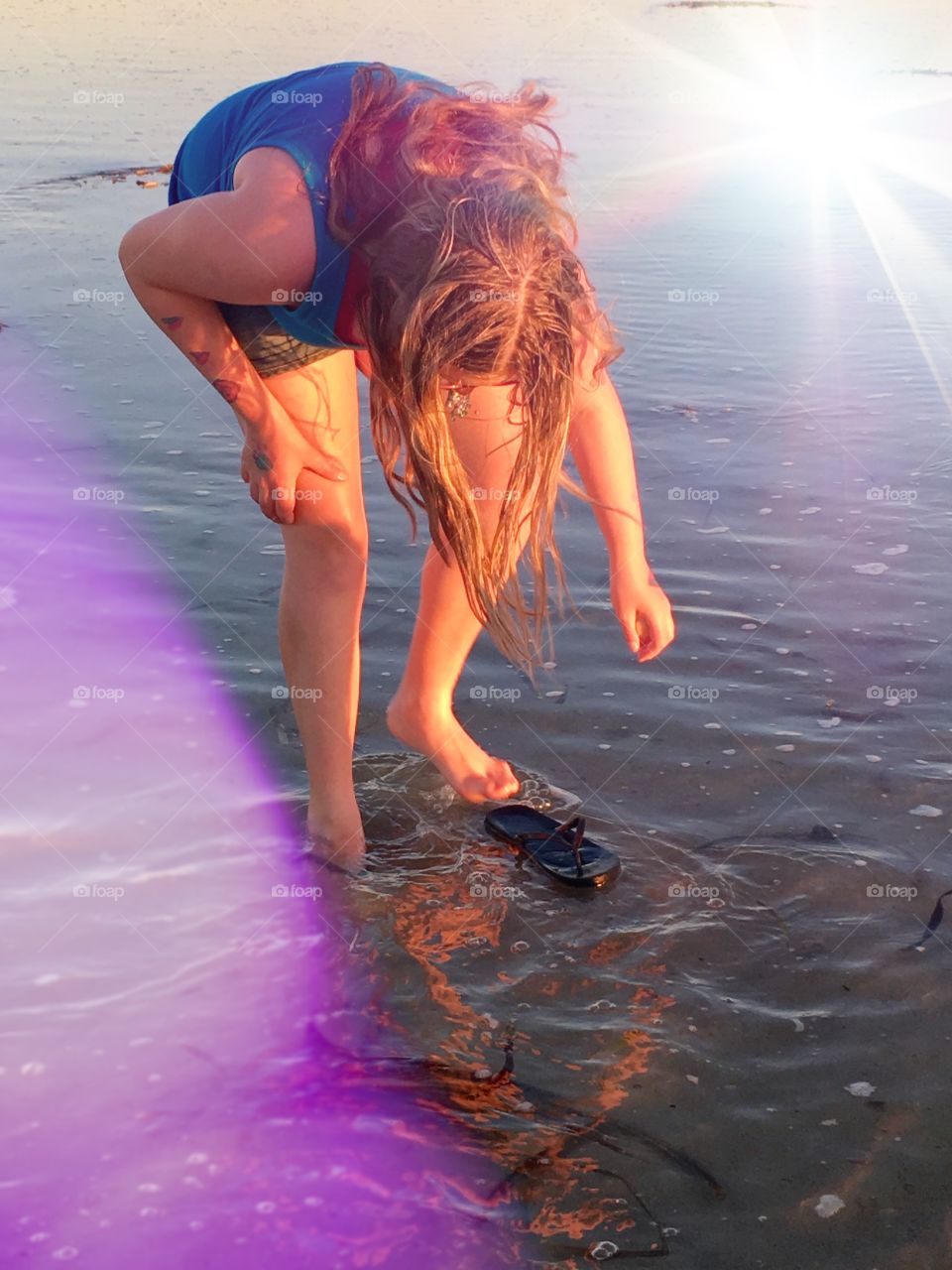 Young girl exploring beach at low tide, in water