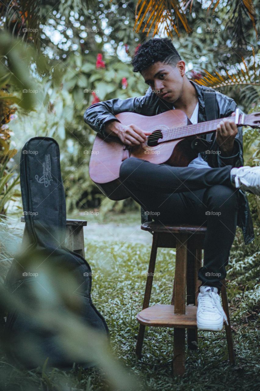 Boy enjoying playing guitar in the middle of nature