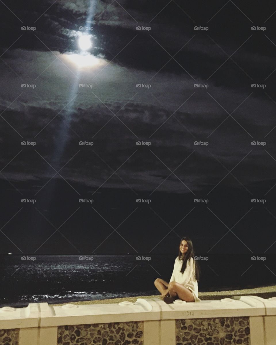 Beautiful woman sitting on breakwater at night