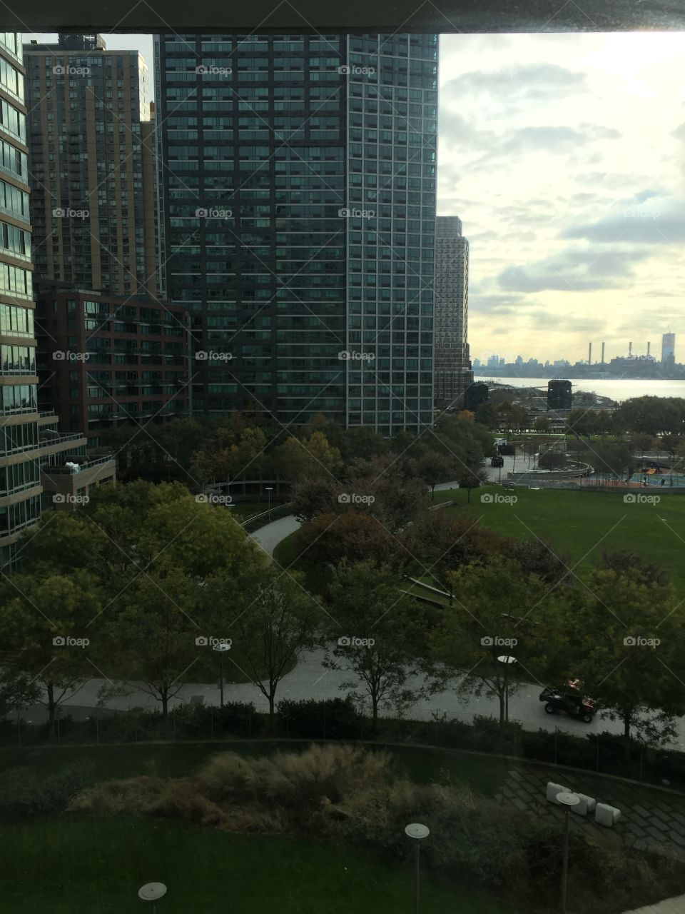 Photo of view of Manhattan from a building . The picture shows the river and the skyscrapers .