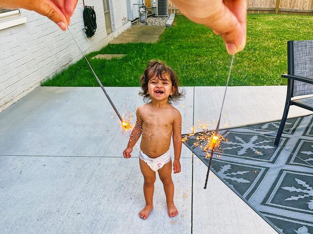 Mother and baby celebrating with sparklers in the backyard, celebrating 4th of July in America, American baby celebrating with sparklers, fireworks in America, celebrating American holidays, 4th of July fireworks in America, backyard party 