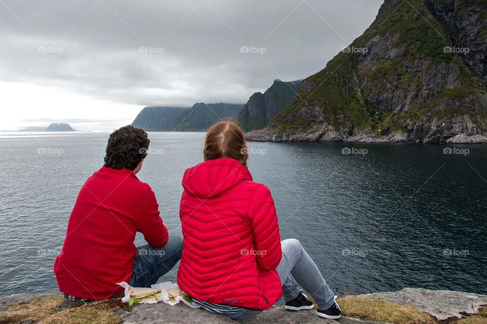 Rear view of two people sitting near lake