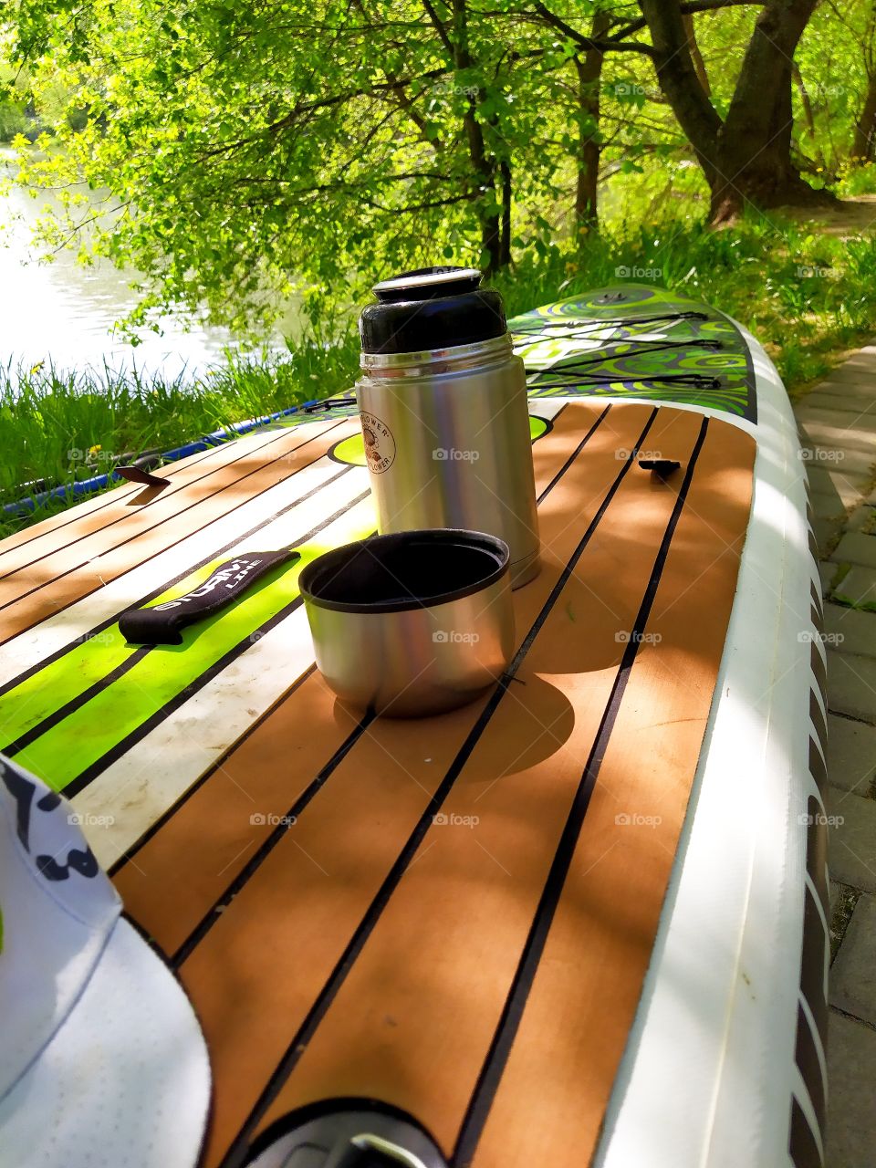 Swimming preparation.  There is an open thermos with hot coffee on the paddleboard