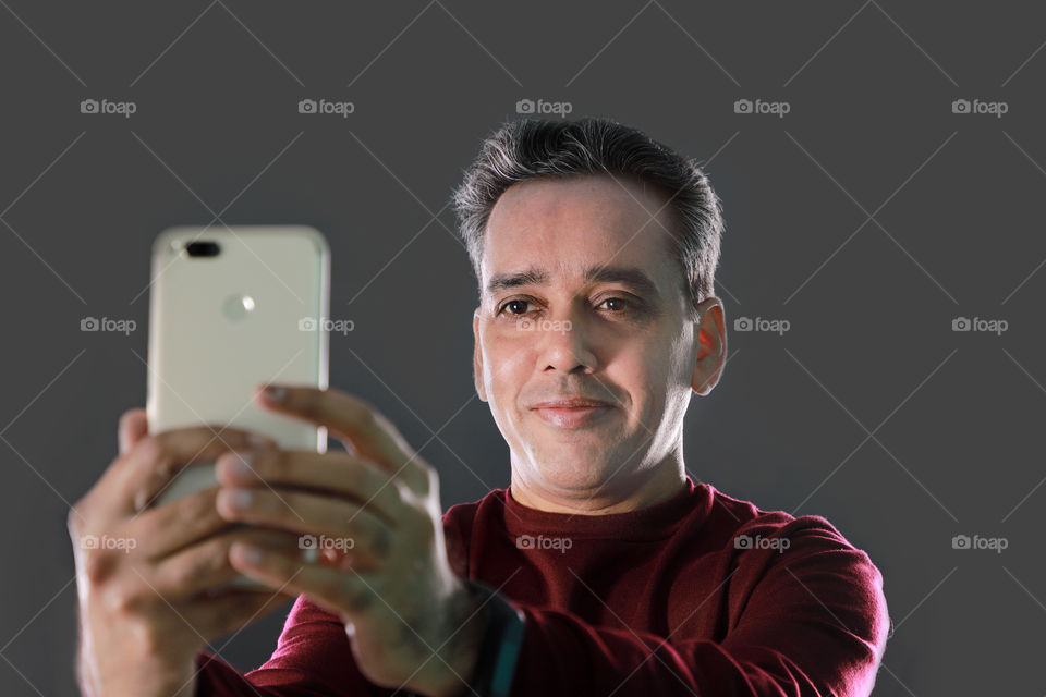 Am Indian man taking a selfie with a mobile phone