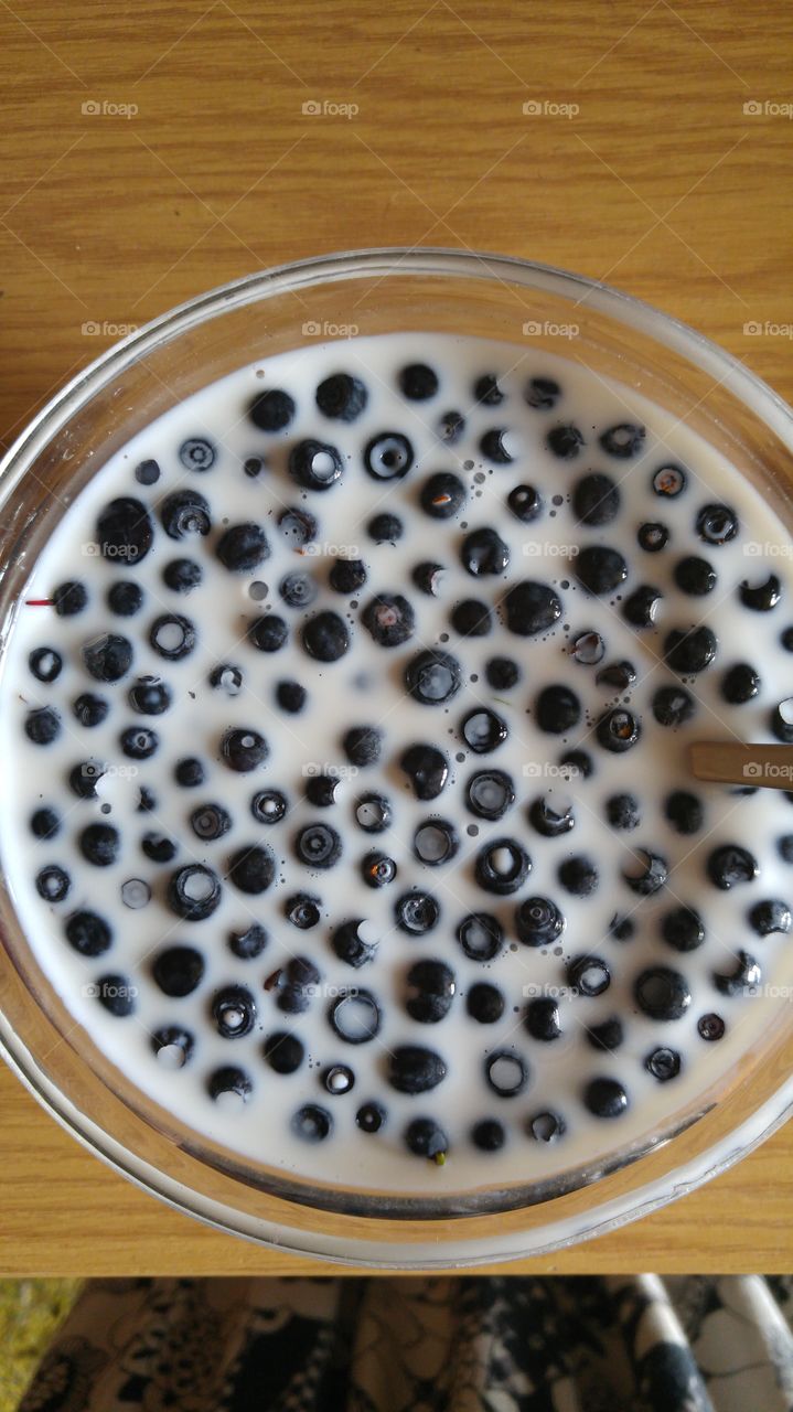 A blueberry desert, berries with a milk in a glass bowl.