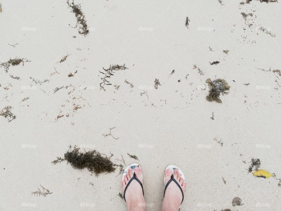 feet in sandals on the sand