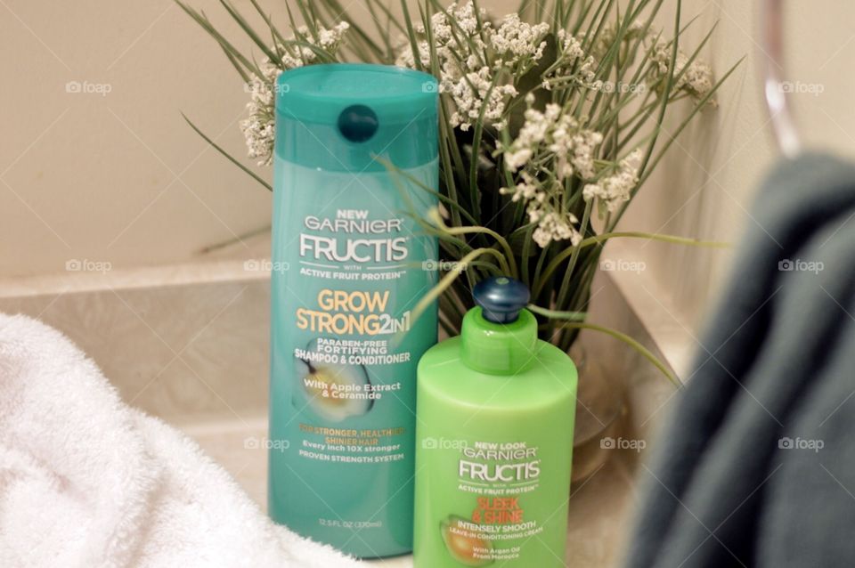 Garnier Two in one shampoo and conditioner and anti-frizz on a bathroom countertop with a white towel