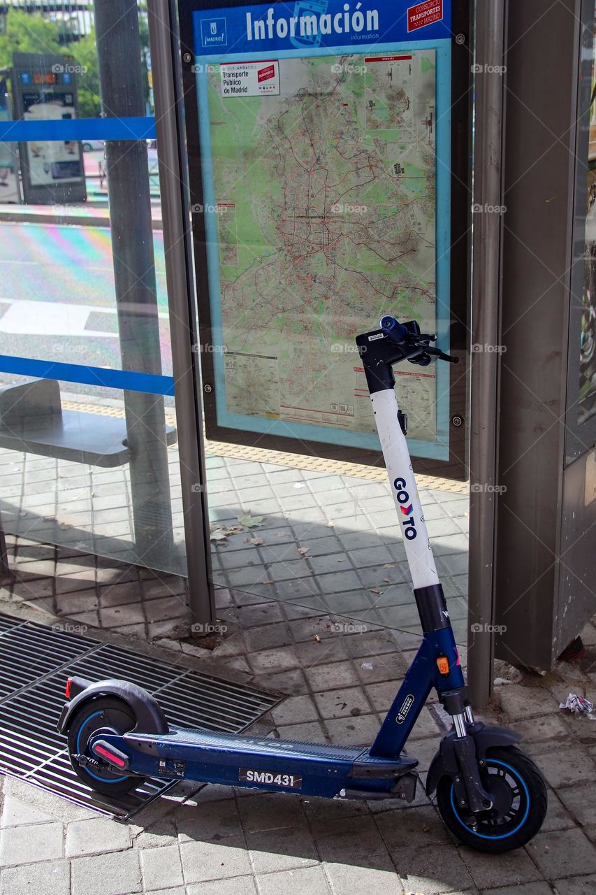 A blue scooter left at a public transport station in Madrid city