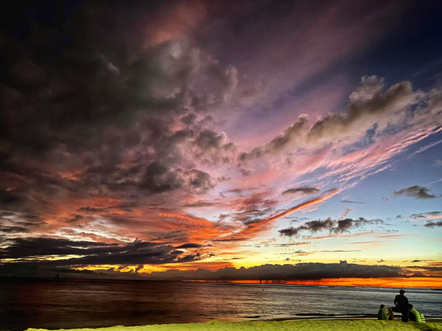 Goodbye 2019... three people watch a dramatic sunset from a narrow strip of shore