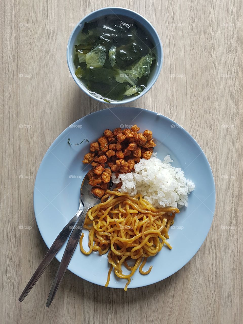 overhead top down flat lay of Asian food served on a plate. Carbohydrates lunch of yellow noodle , rice, crispy soi and seaweed soup