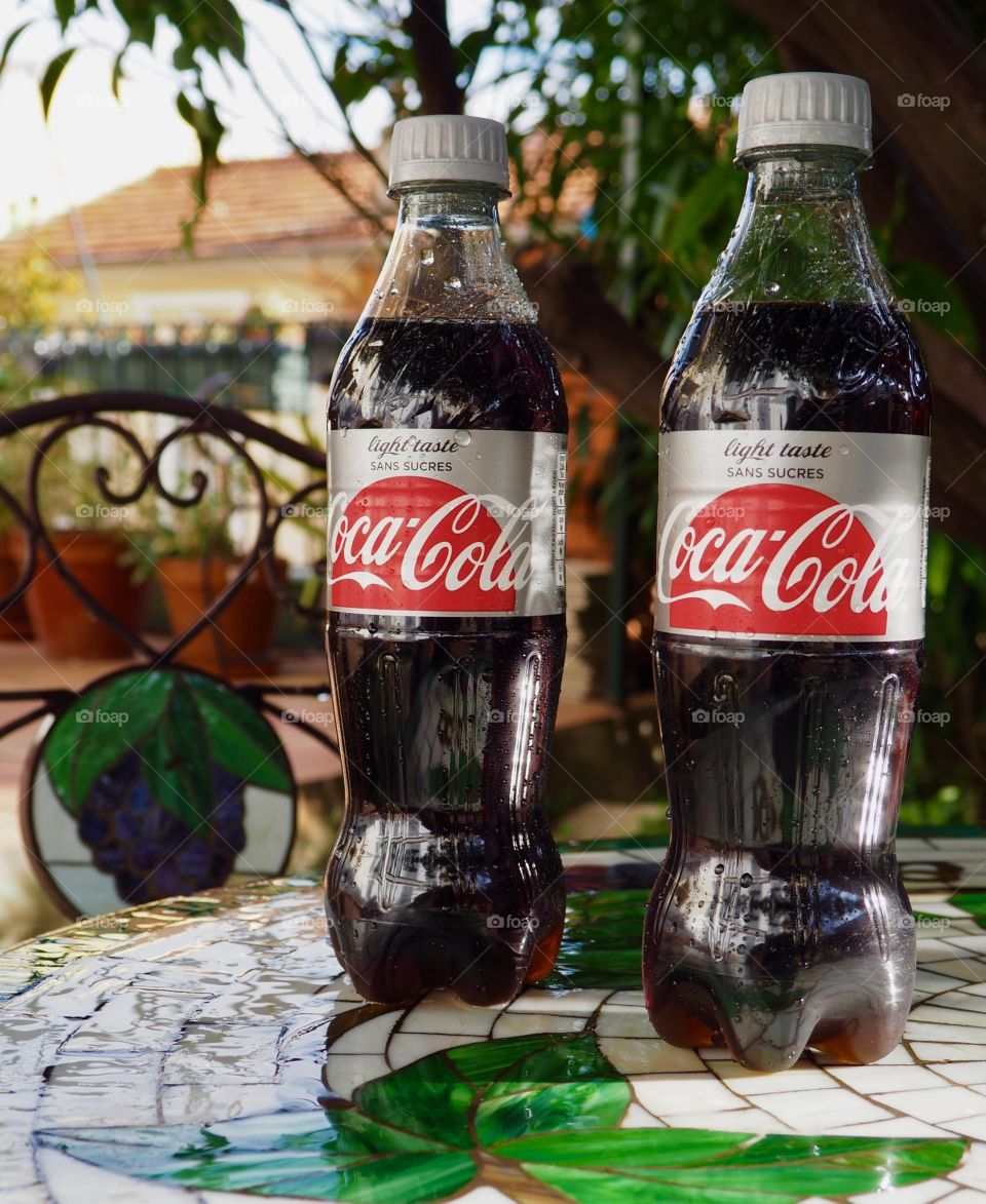 Two Diet Coke bottles on garden table.