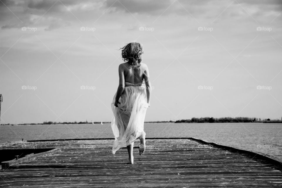 woman in dress running. woman in beautiful dress running on deck towards lake