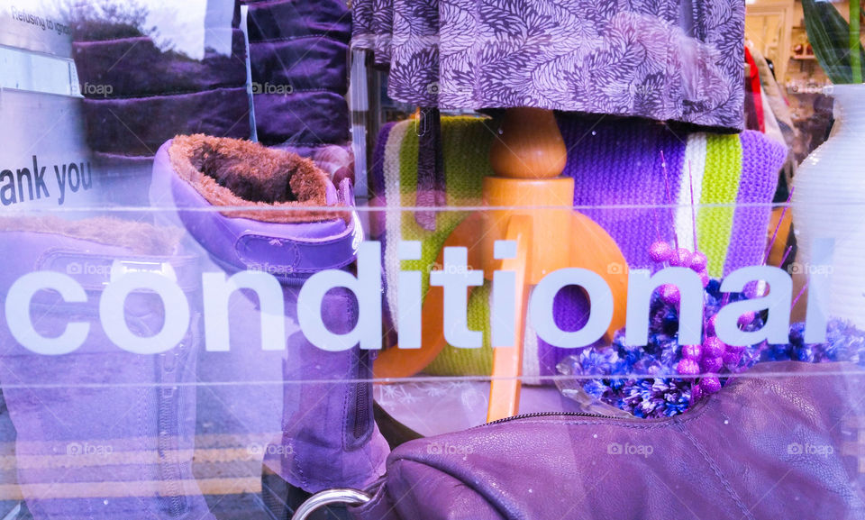 A purple display in a charity shop window with the letters "conditional" across