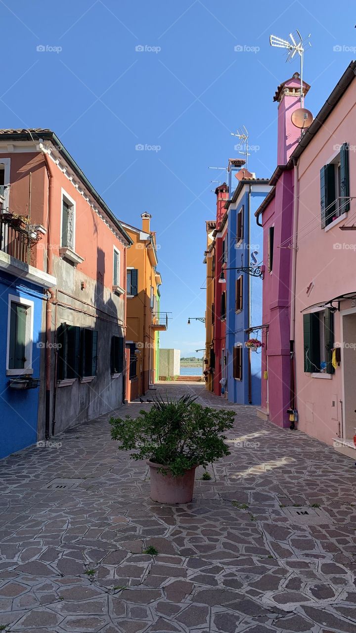 A narrow alley lined with brightly colored houses under a clear sky – Mediterranean charm in full color.