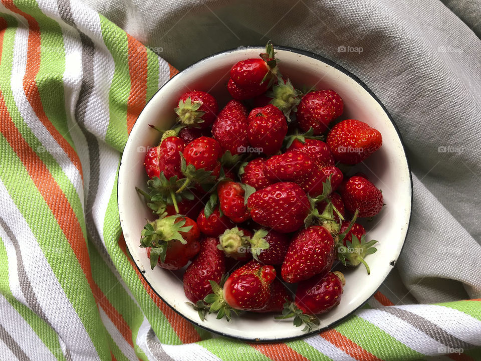 Rustic bowl of ripe red strawberries on rustic textile background 