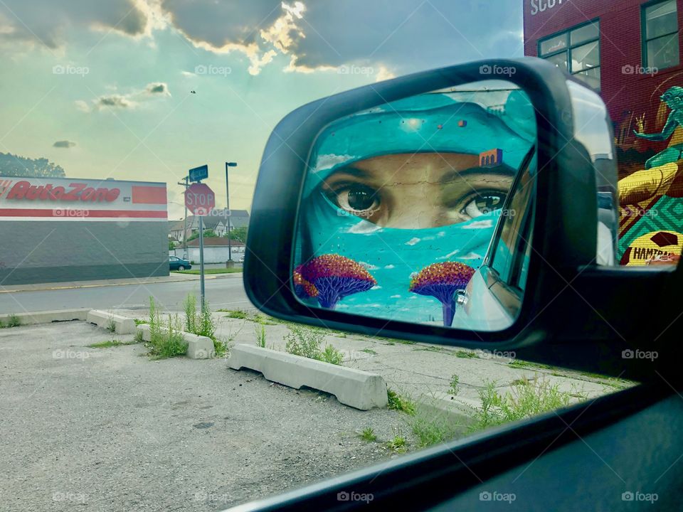 A reflection of mural of a two Yemeni traditional marked: Niqab and Dracaena cinnabari. The mural is located in Hamtramck, Michigan. 