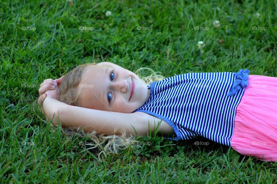 Smiling little girl lying on green grass