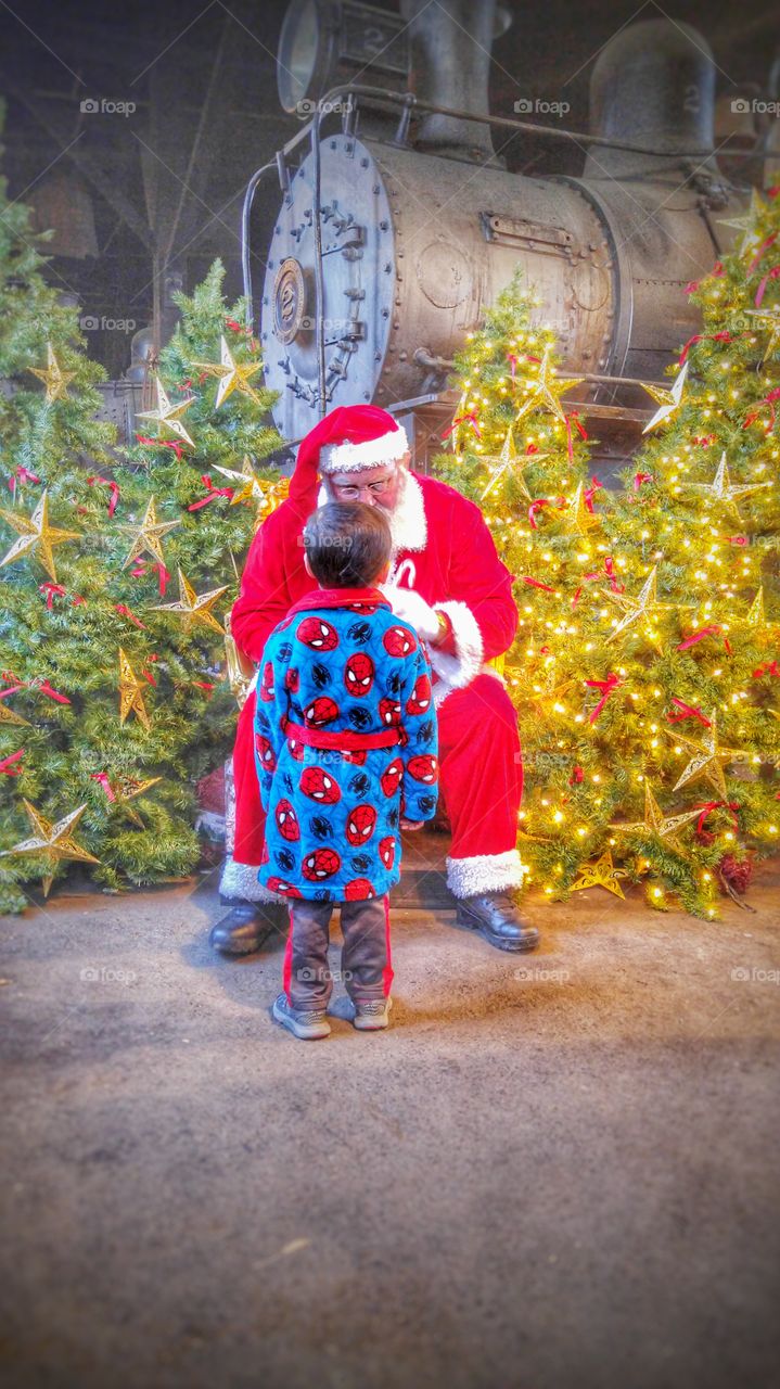Santa claus and little boy sitting in front christmas tree