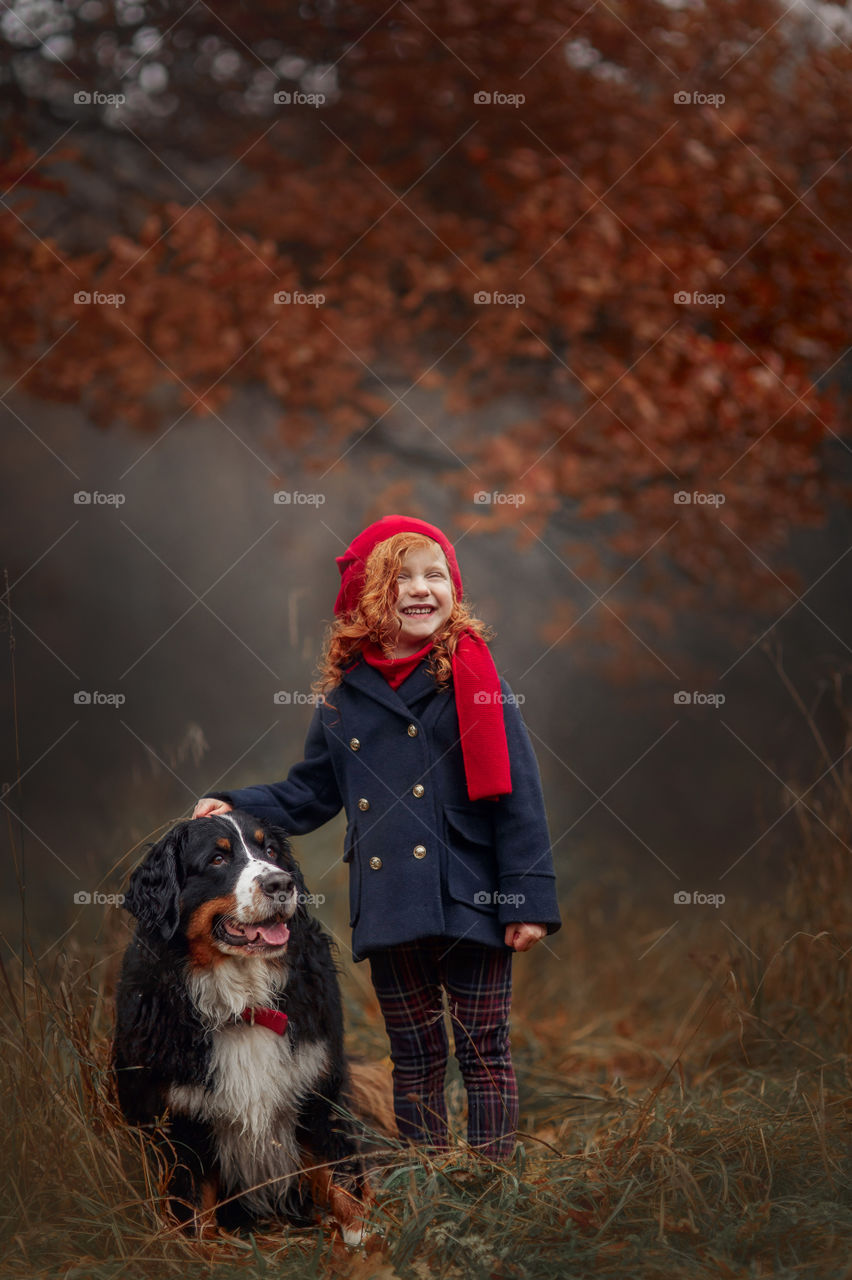 Little girl with dog in autumn park 