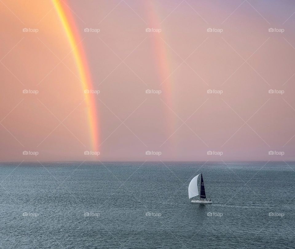 Double rainbow at sea above a sailboat