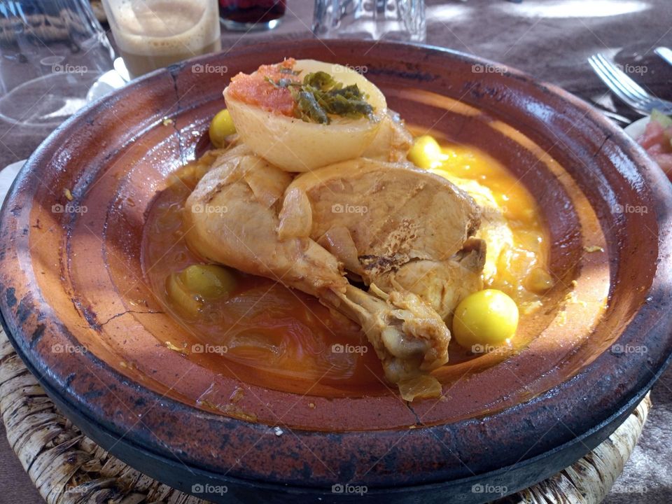 A Moroccan Lemon Chicken Dish served in a Sauce with Green Olives. The Chicken is left on the Bone. The Dish is lightly Garnished.