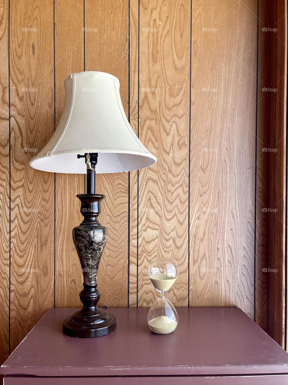 Retro lamp with hourglass on the wooden background 