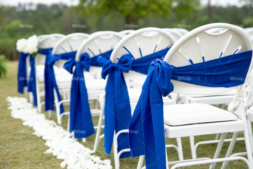 white wedding ceremony chairs with blue bows and ribbons