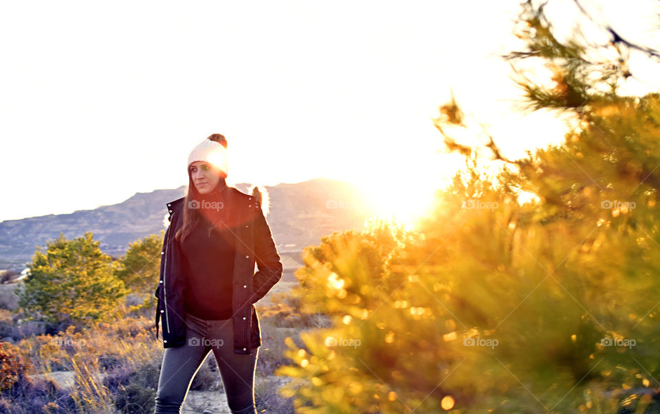 Cute woman wandering at countryside during winter at sunset