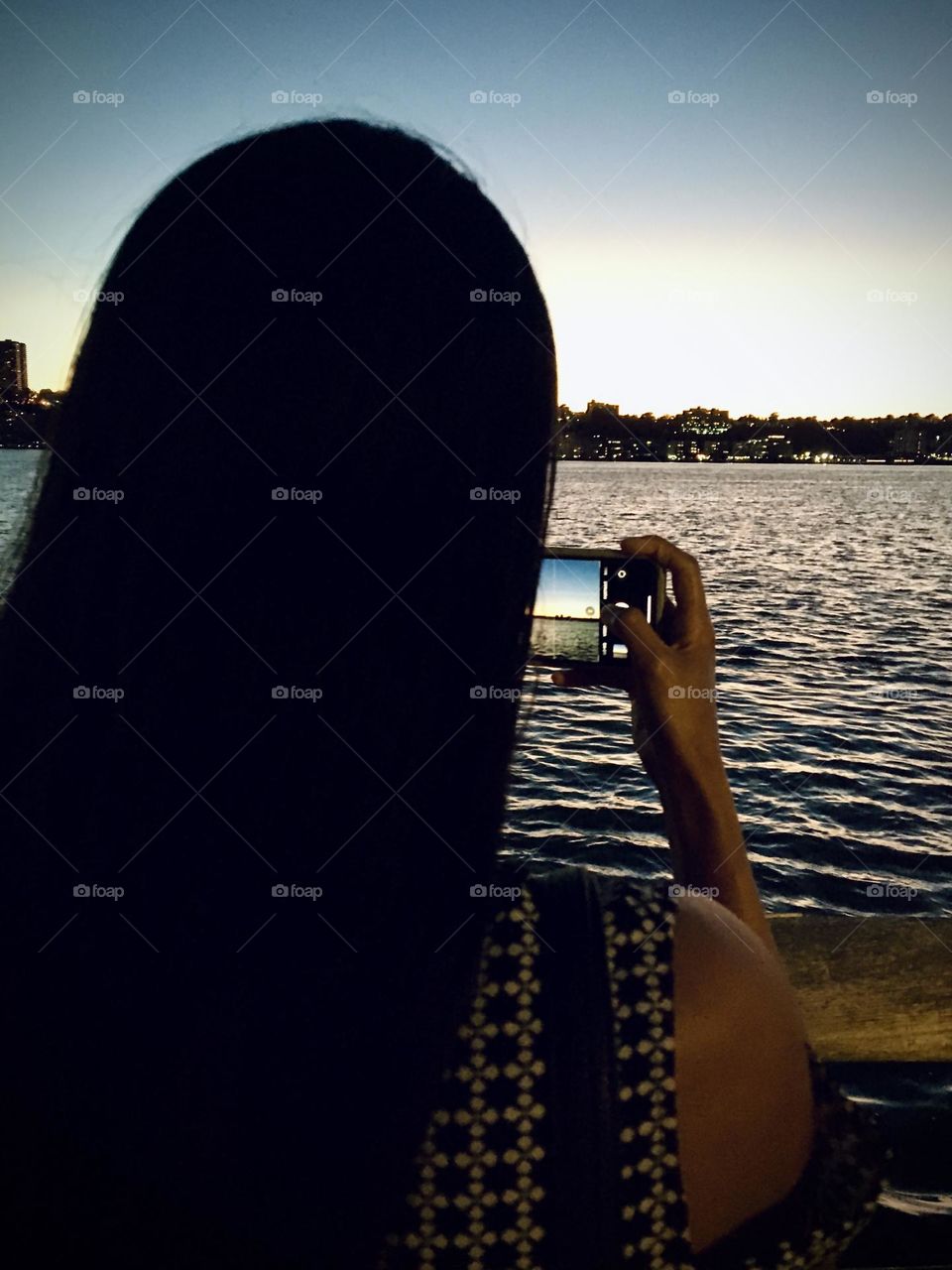 A woman taking a picture of the Riverside Park using an iPhone 