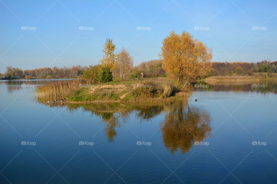 autumn beautiful landscape lake shore and reflection and person walking blue sky background, nature lovers