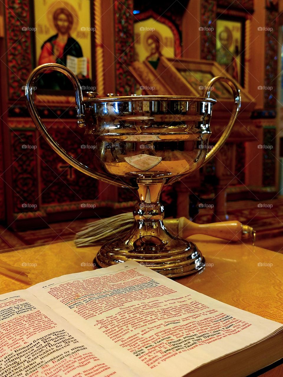 Minimalism of objects that are connected by one meaning.  Church.  On the stand is an open Bible, a bowl of holy water and a sprinkler.  Objects on the background of icons