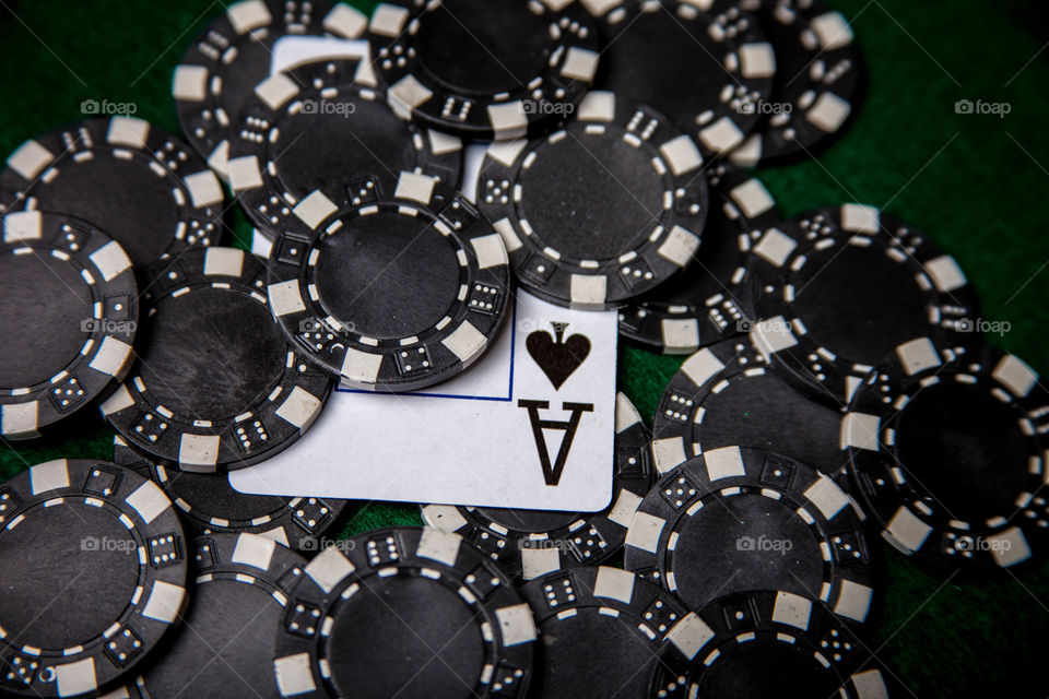 Ace of Spades in black chips. This is a photograph of an Ace of Spades under black poker chips.