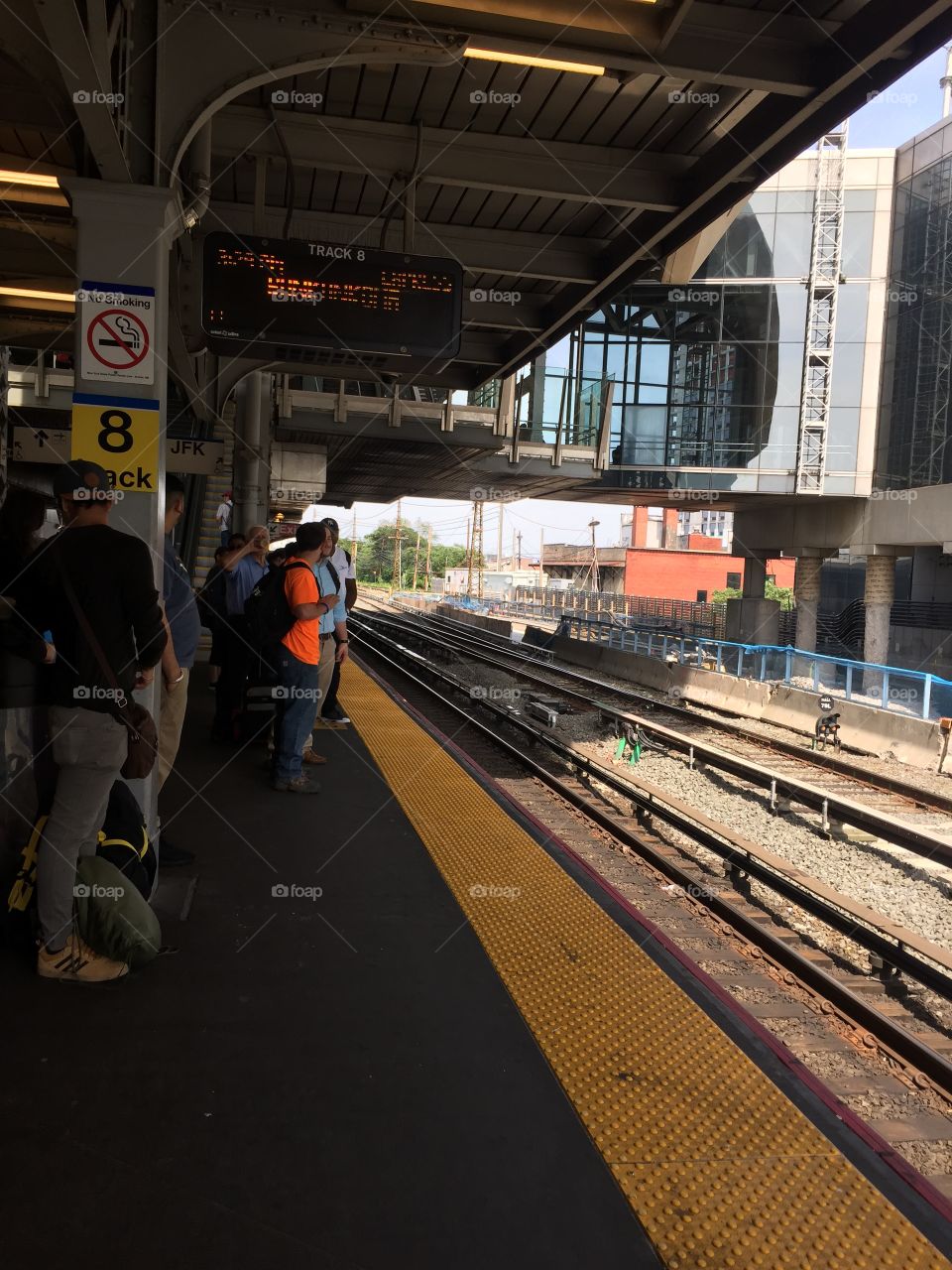 Long Island Rail Road train platform in Jamaica, New York City with commuters and train tracks.
