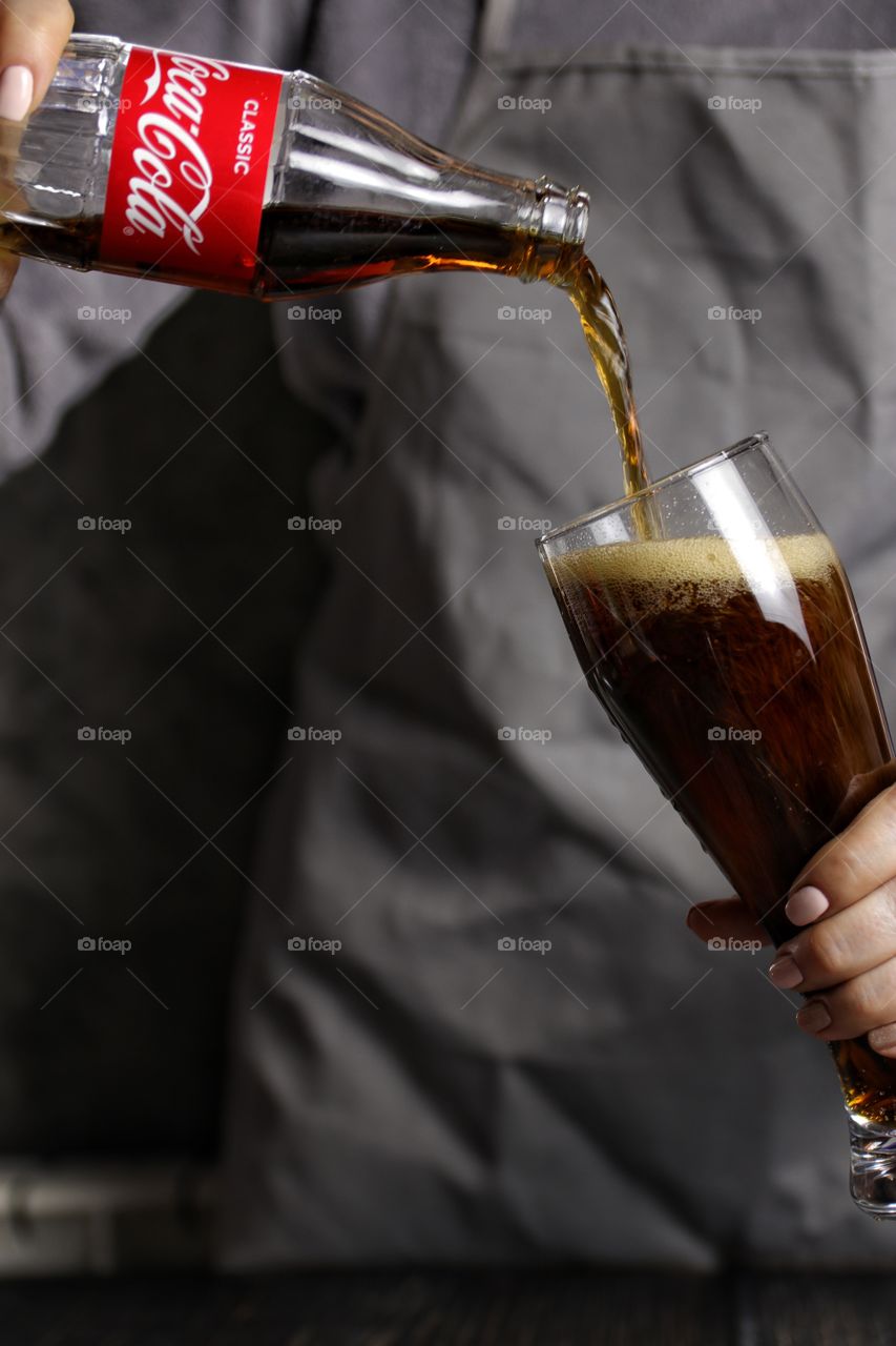 Female hands with a bottle of coca cola and glass 