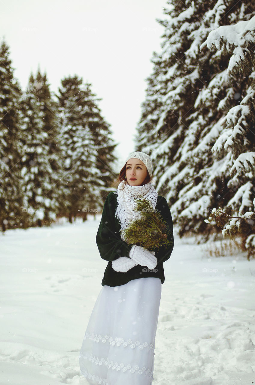 Winter portrait of young redhead woman in green sweater in snowcovered winter park.