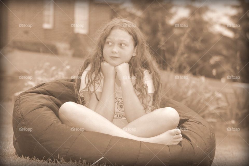 Girl sitting on bean bag in garden